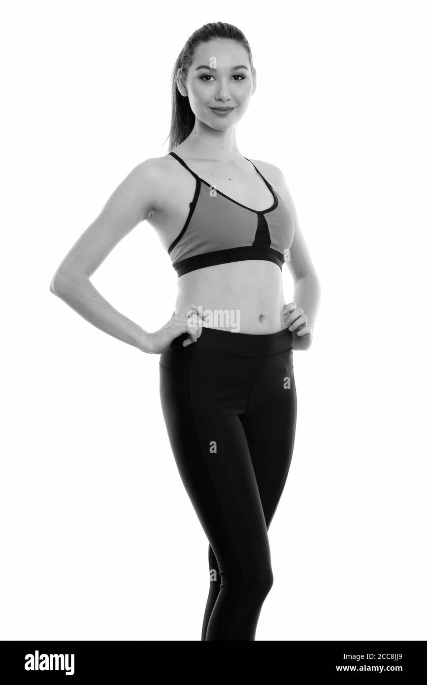 Studio shot del giovane bella donna asiatica in posa con entrambe le mani sui fianchi pronta per la palestra Foto Stock