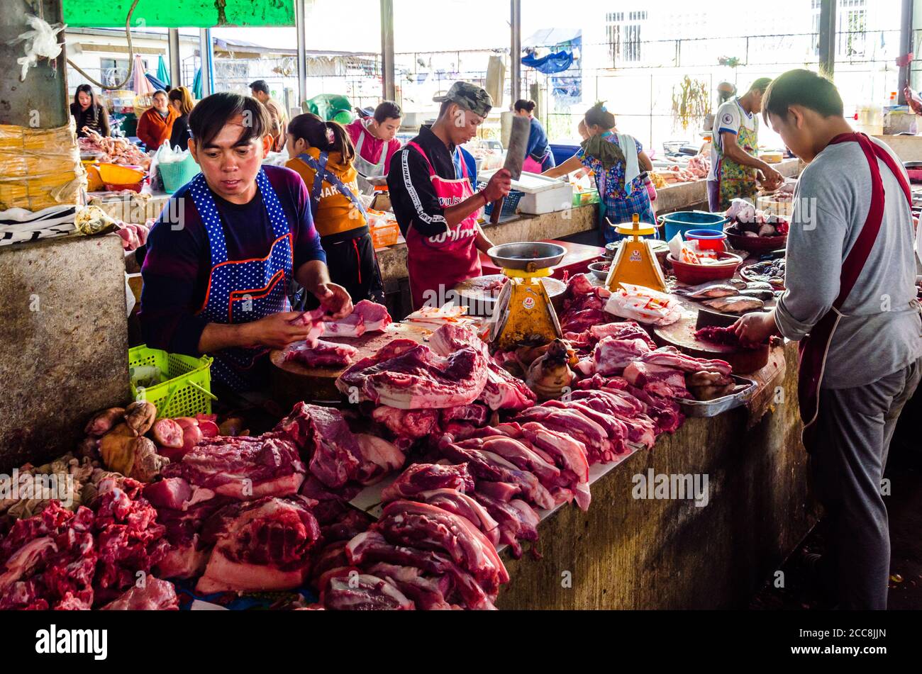 Tachileik, Myanmar - 8 febbraio 2019: Commercianti maschi nel loro stand che vendono carne nel mercato umido in Myanmar. Gli uomini offrono carne rossa. Foto Stock