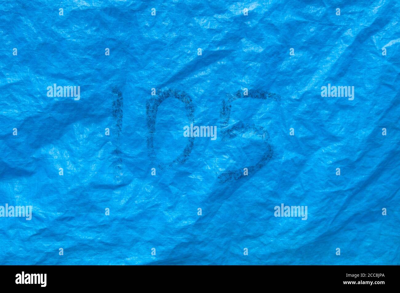 Il numero 105 scritto a mano in penna su un blu luminoso Telone in plastica Foto Stock