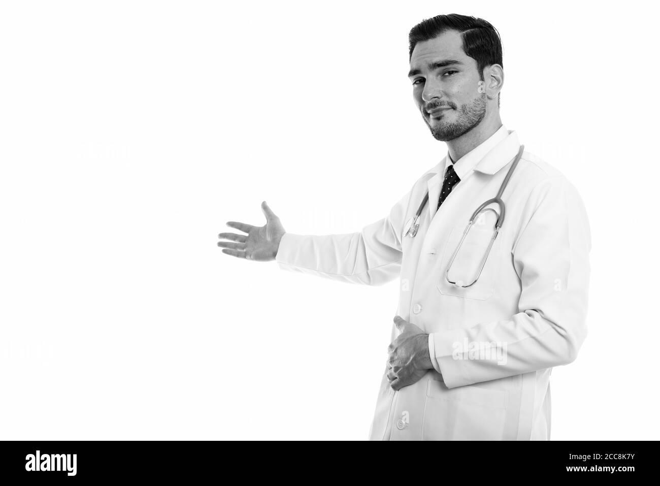 Studio shot del giovane uomo bello medico mostrando qualcosa sulla parete Foto Stock