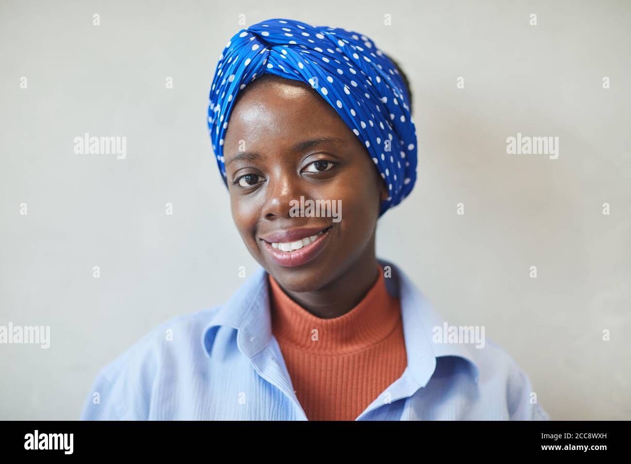 Ritratto di giovane donna africana con bella sciarpa su di lei testa sorridente alla fotocamera Foto Stock