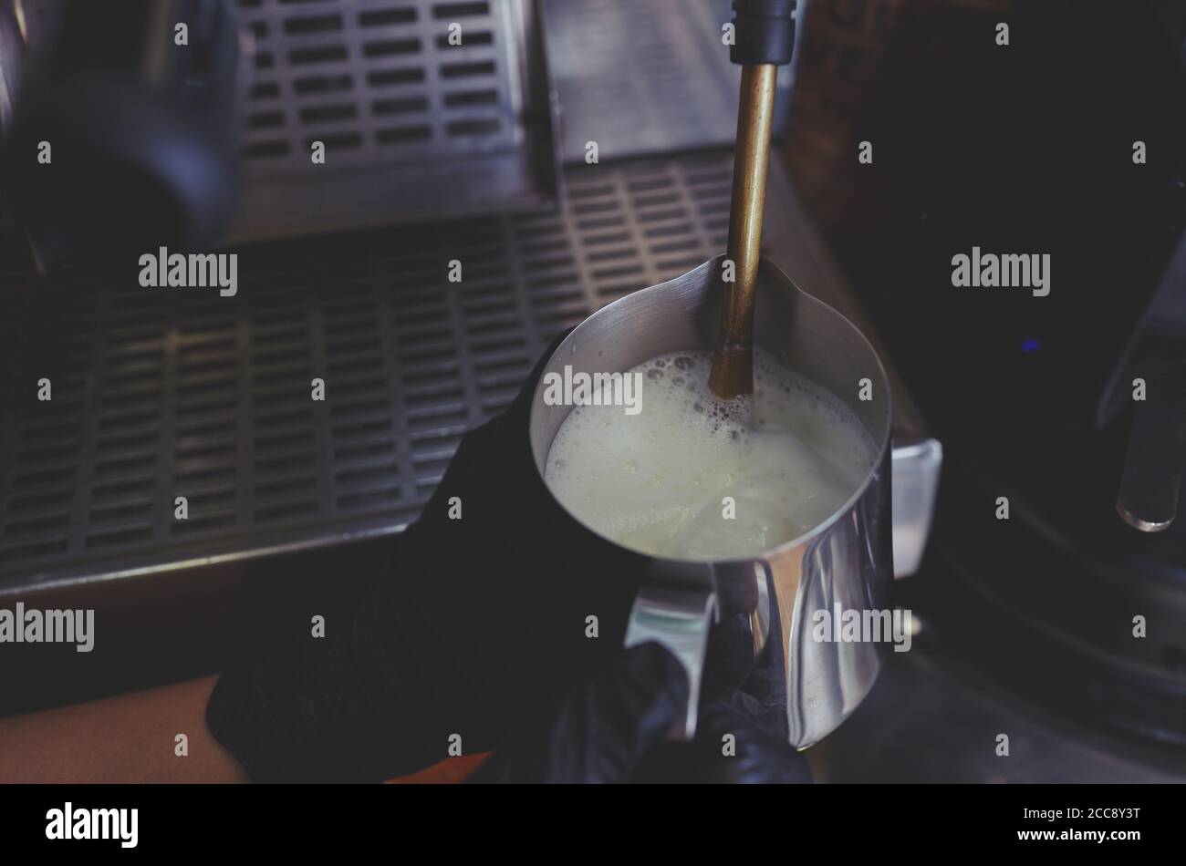 Preparare la schiuma di latte sotto pressione da una macchina da caffè in caraffa Foto Stock