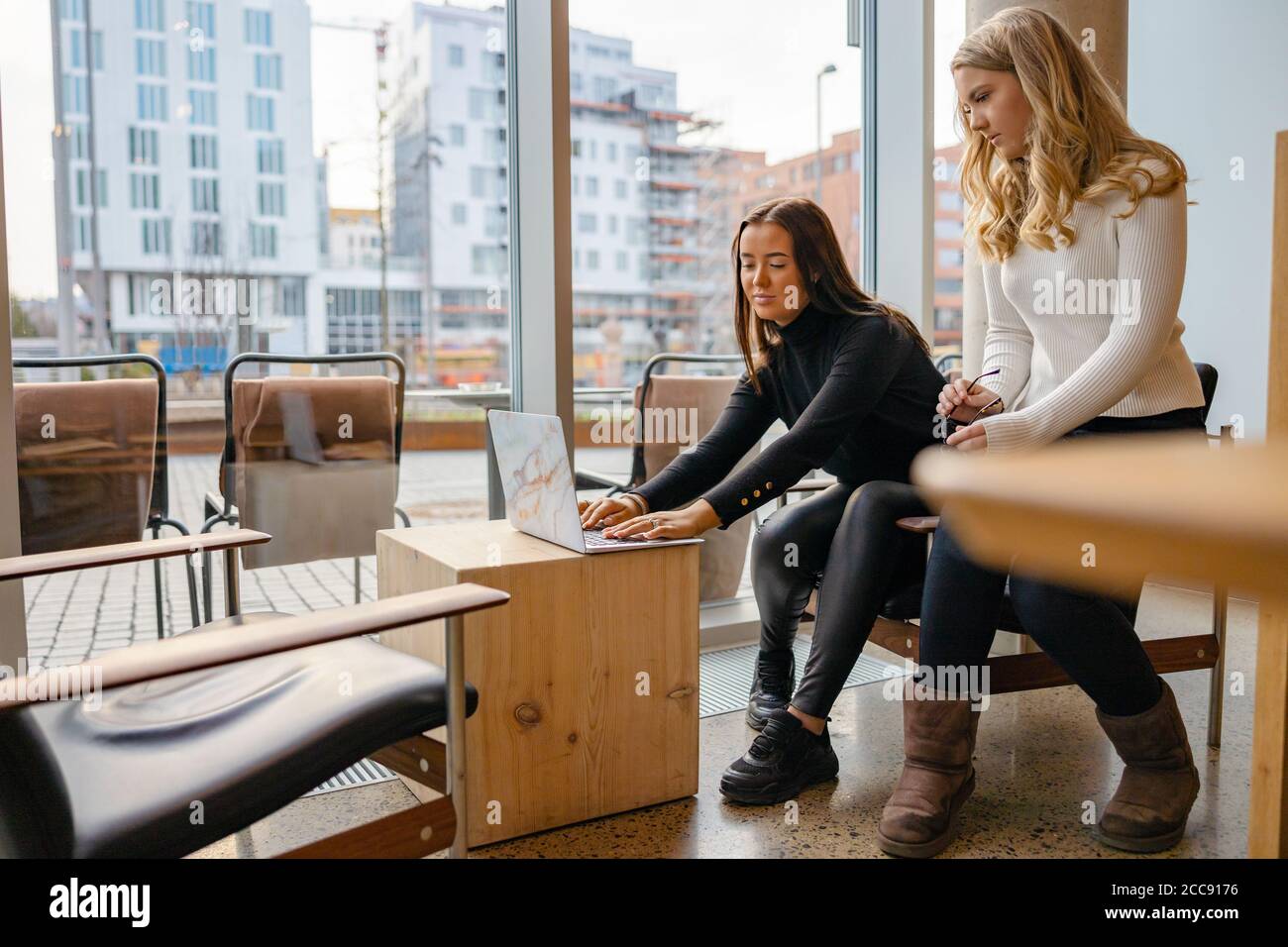 Amici che lavorano insieme al computer portatile al Cafe di City Foto Stock