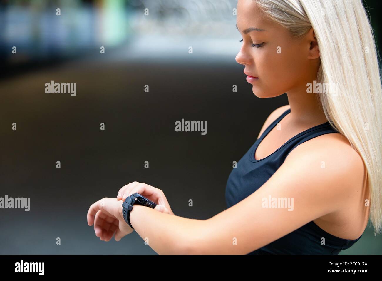 Profilo di Female Runner Checking Smartwatch dopo l'allenamento su strada Foto Stock