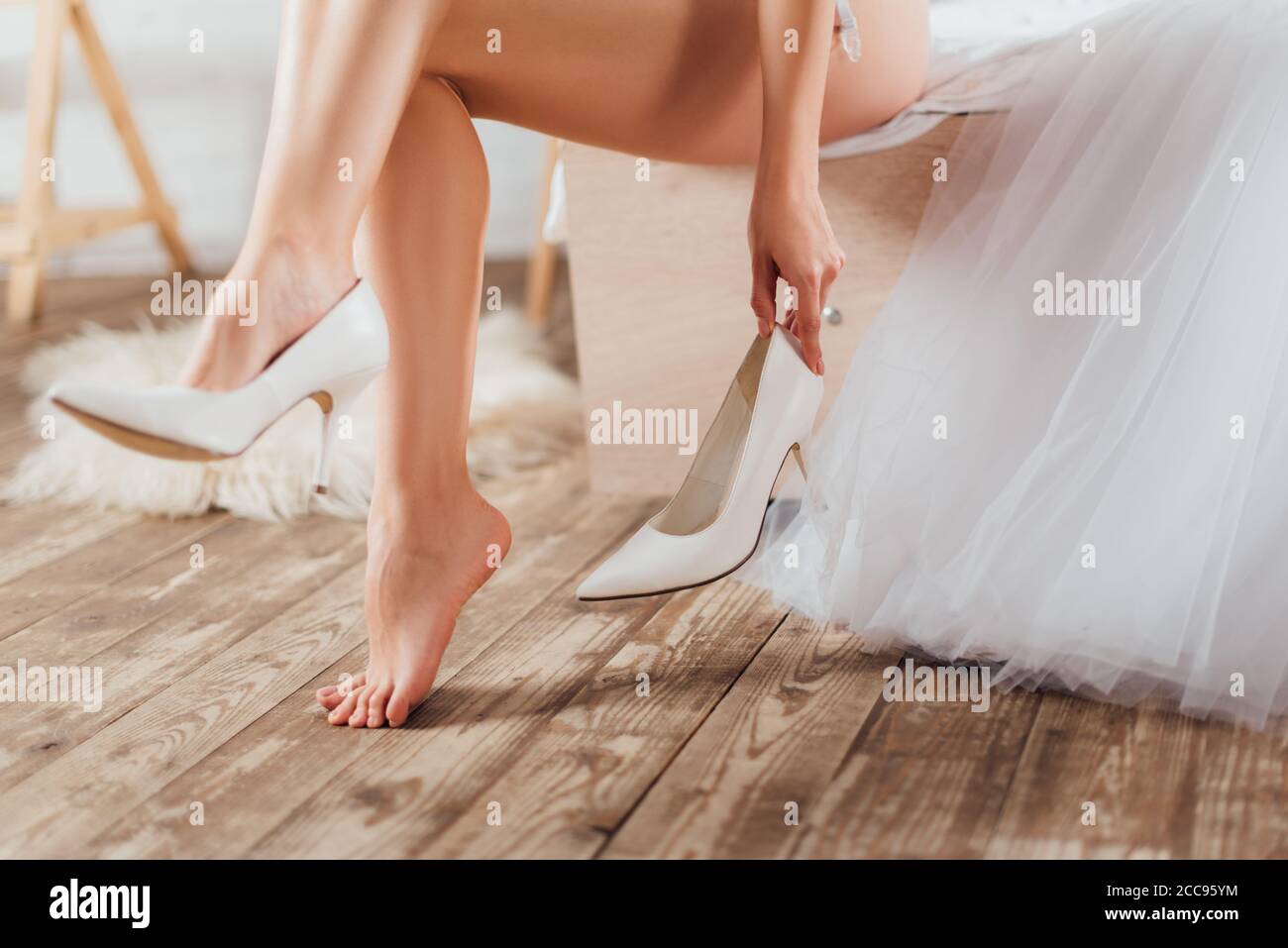 Vista dal taglio della sposa che indossa tacchi da sposa vicino all'abito a letto Foto Stock
