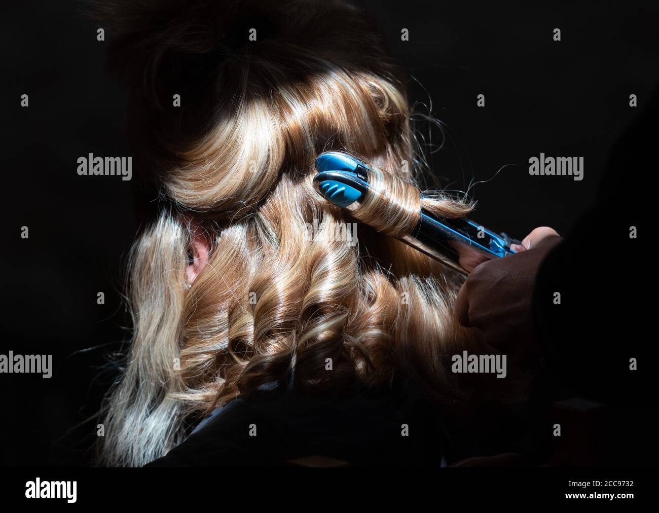 Acconciatura. Piastra per capelli sui capelli biondi della sposa Foto Stock