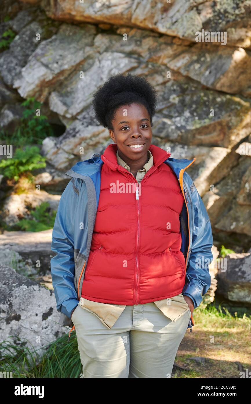 Ritratto di giovane donna africana in abiti caldi che sorride macchina fotografica durante le escursioni Foto Stock