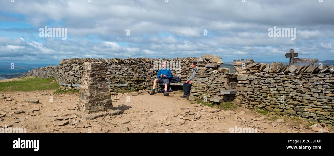 Due escursionisti seduti per ammirare la vista dal rifugio sulla cima di Pen-y-Ghent, una delle tre vette dello Yorkshire Foto Stock