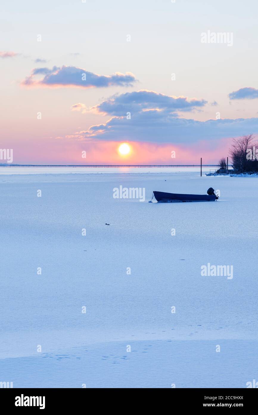 Barca in una baia ghiacciata di Fehmarn suono al tramonto Foto Stock