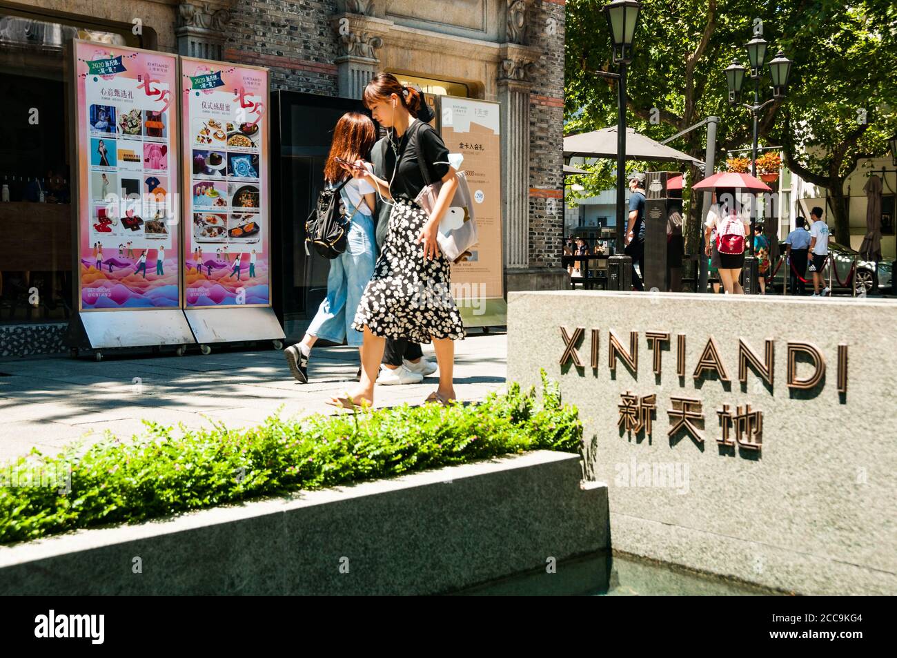 Una giovane donna che guarda il suo telefono entra Xintiandi a Shanghai. Foto Stock