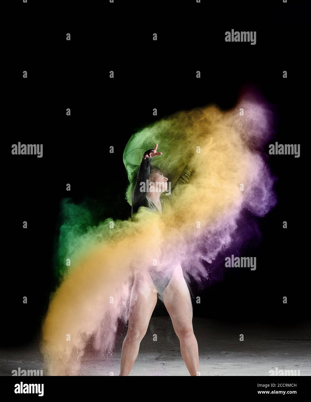 bella donna caucasica in un corpo nero con uno sport il personaggio sta ballando in una nuvola multicolore di farina sopra uno sfondo nero Foto Stock
