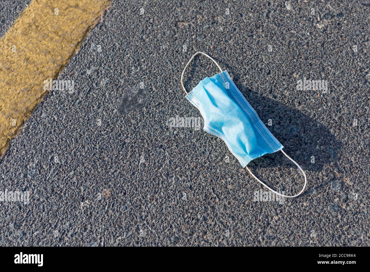 Usato maschera medica monouso gettata sulla strada. Inquinamento e rifiuti durante la pandemia di Covid-19. Foto Stock