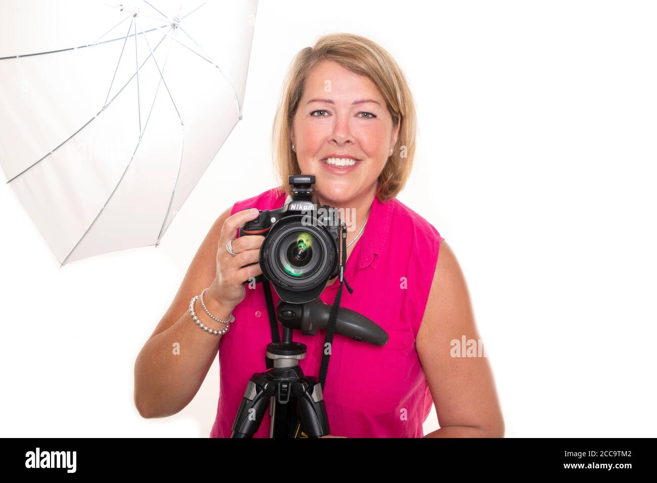 Ritratto orizzontale di una fotografa femminile in piedi dietro un treppiede per scattare foto in uno studio. Foto Stock
