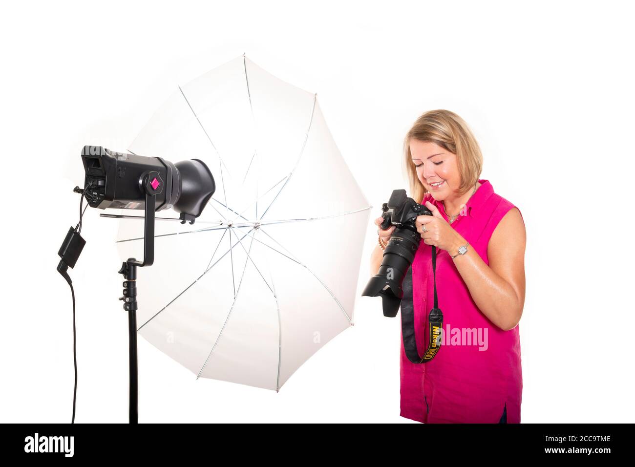 Ritratto orizzontale di un fotografo che controlla le immagini sul retro di una fotocamera DSLR mentre lavora in uno studio. Foto Stock