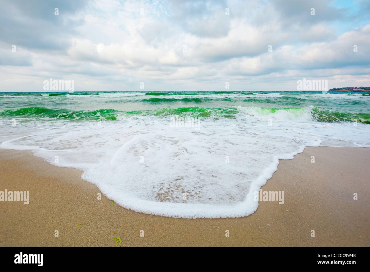il mare verde ondeggia sotto un cielo grigio. marea che si ondola sulla spiaggia. scenario vuoto e tranquillo. concetto di solitudine Foto Stock
