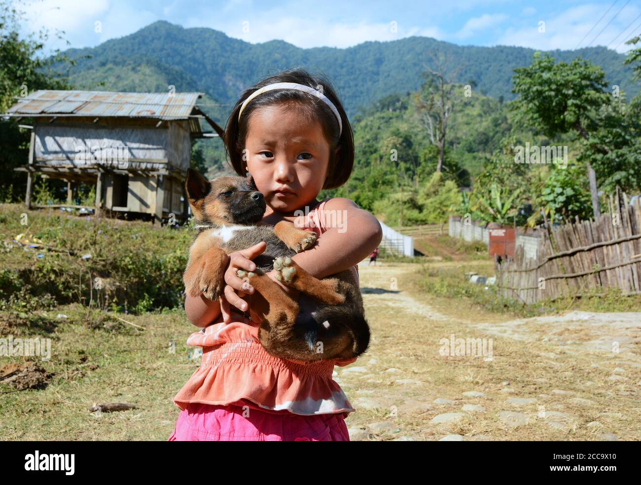 La bambina che gioca con il suo animale domestico davanti alla sua piccola casa ad Arunachalpradesh, India. Foto Stock