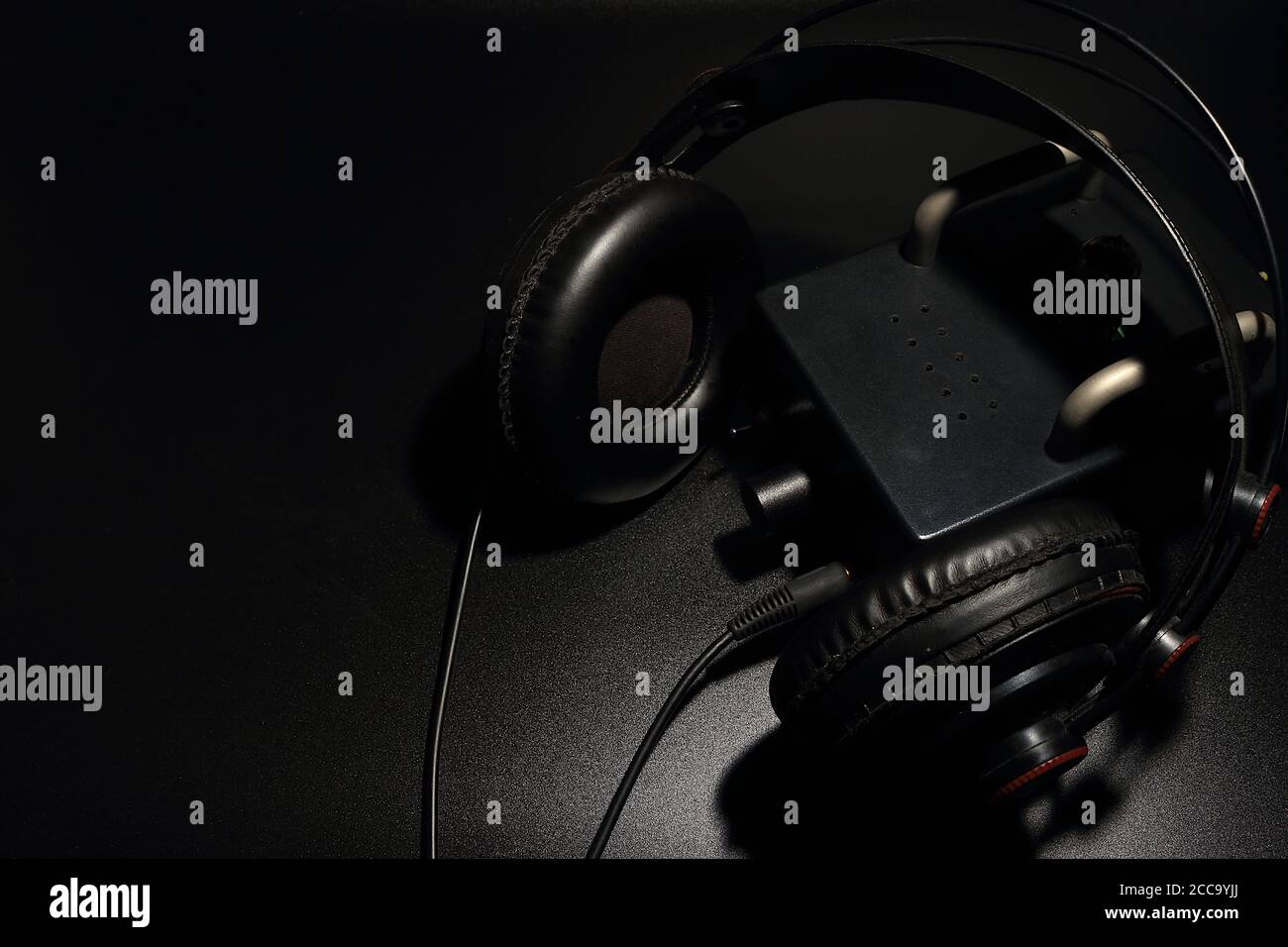 Le cuffie di dimensioni standard sono posizionate con un preamplificatore a tubo su uno sfondo nero. Foto Stock