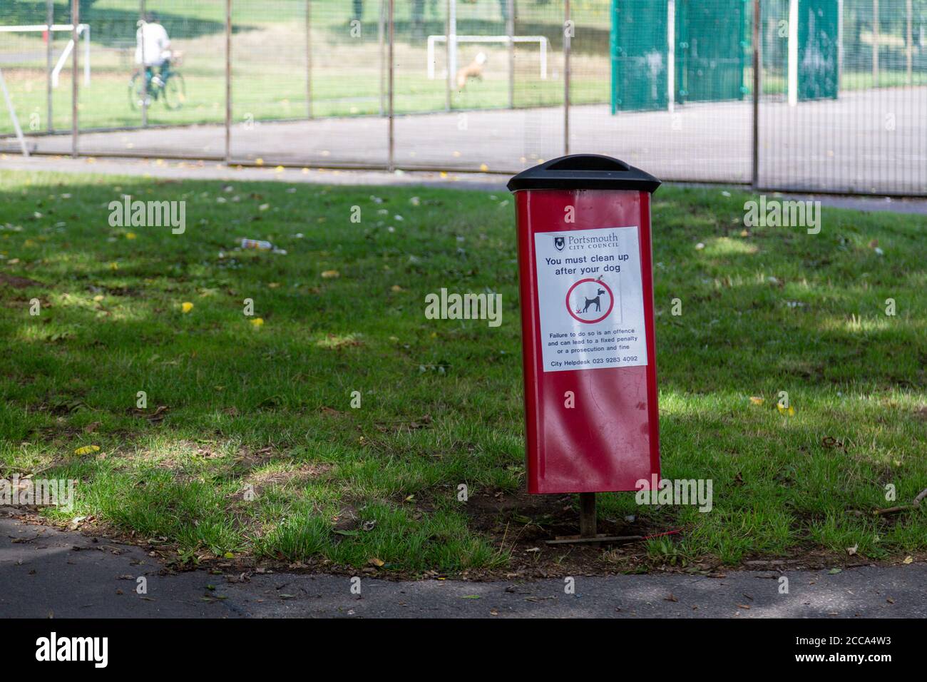 Un cestino di rifiuti per cani nel mezzo di un parco Foto Stock