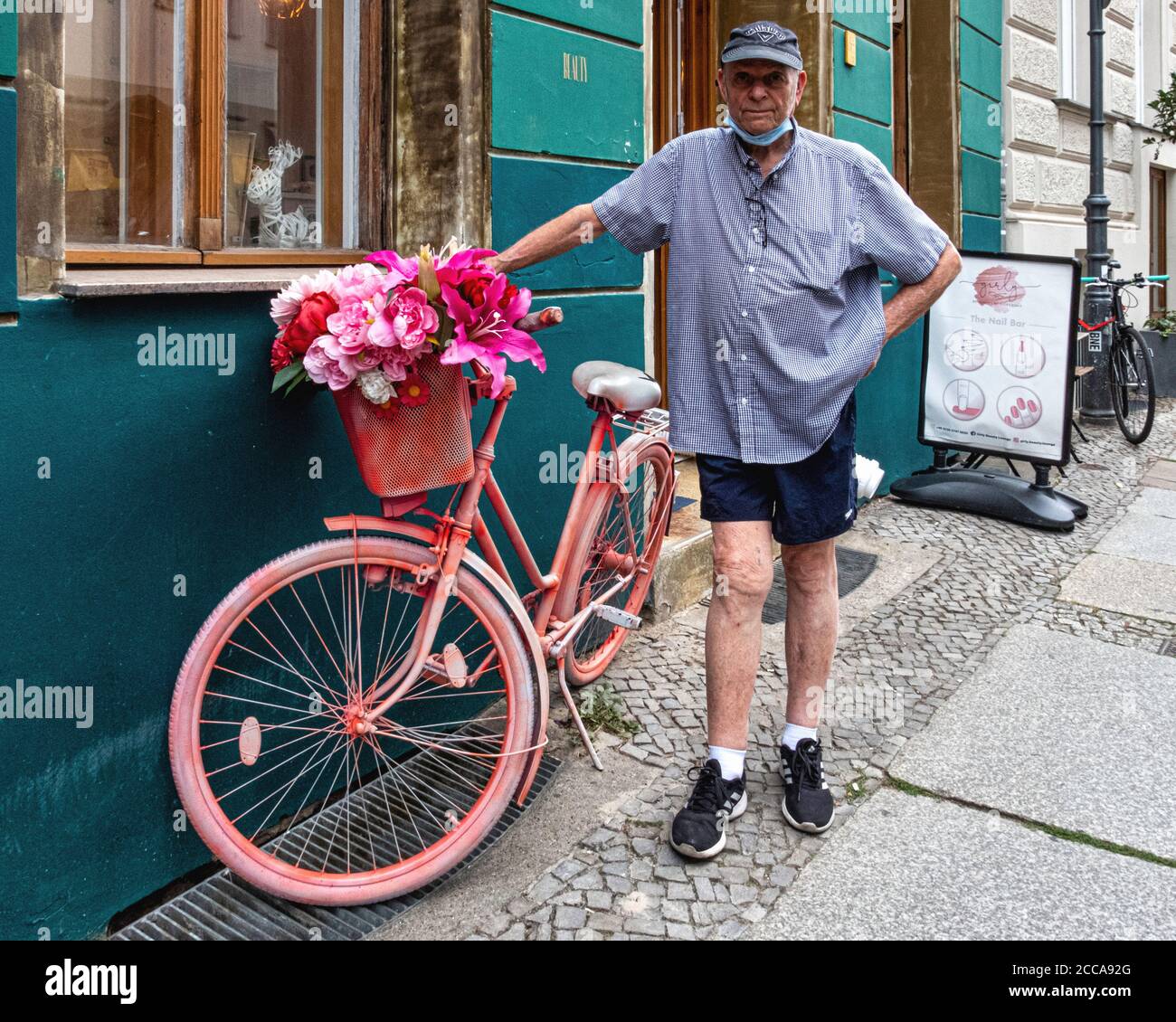 Bicicletta rosa all'esterno del negozio Girly Beauty Lounge e uomo anziano Con maschera sotto chin.Mulackstrasse, Mitte, Berlino Foto Stock