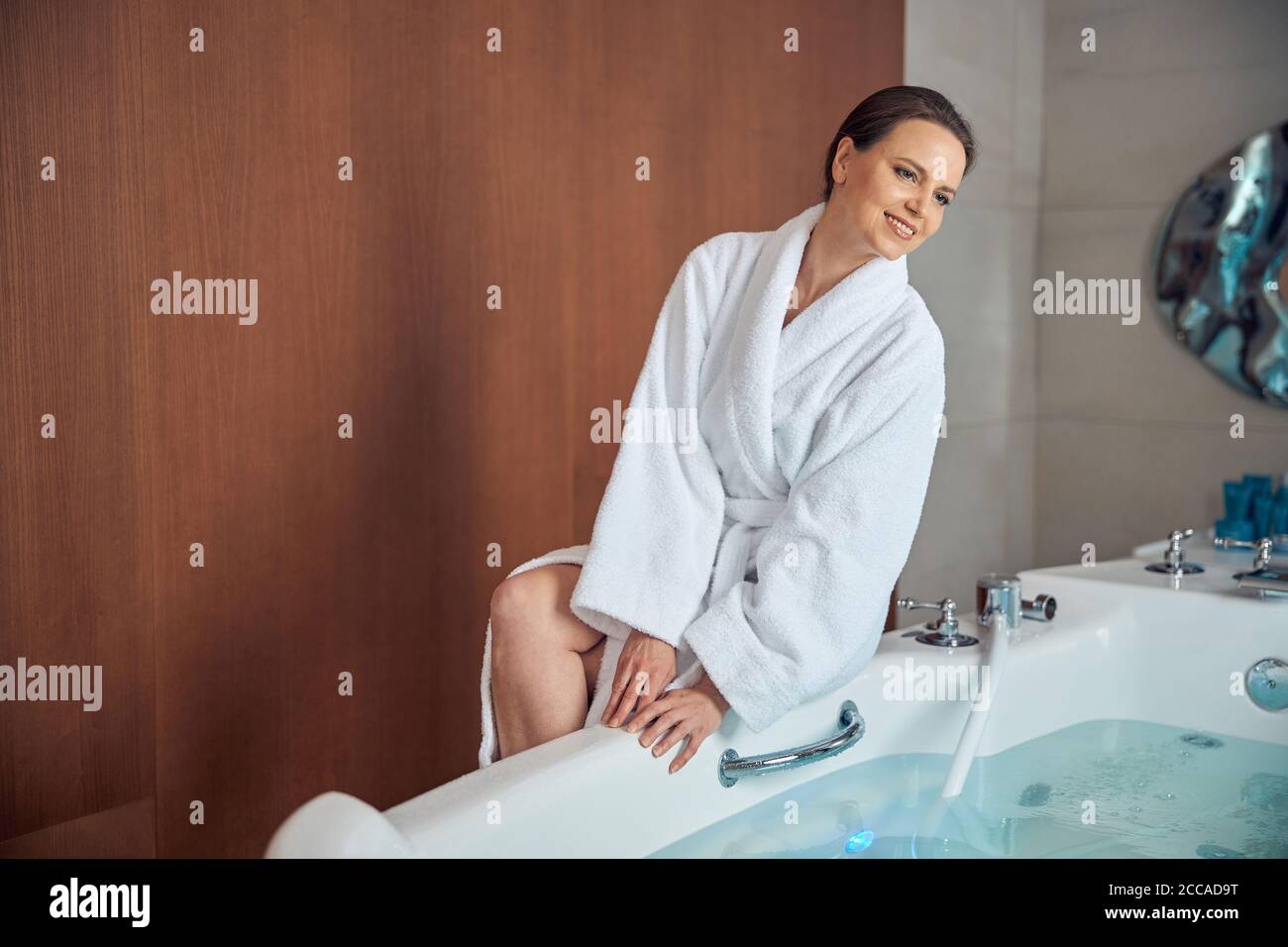 Donna seduta sul bordo della vasca da bagno Foto Stock