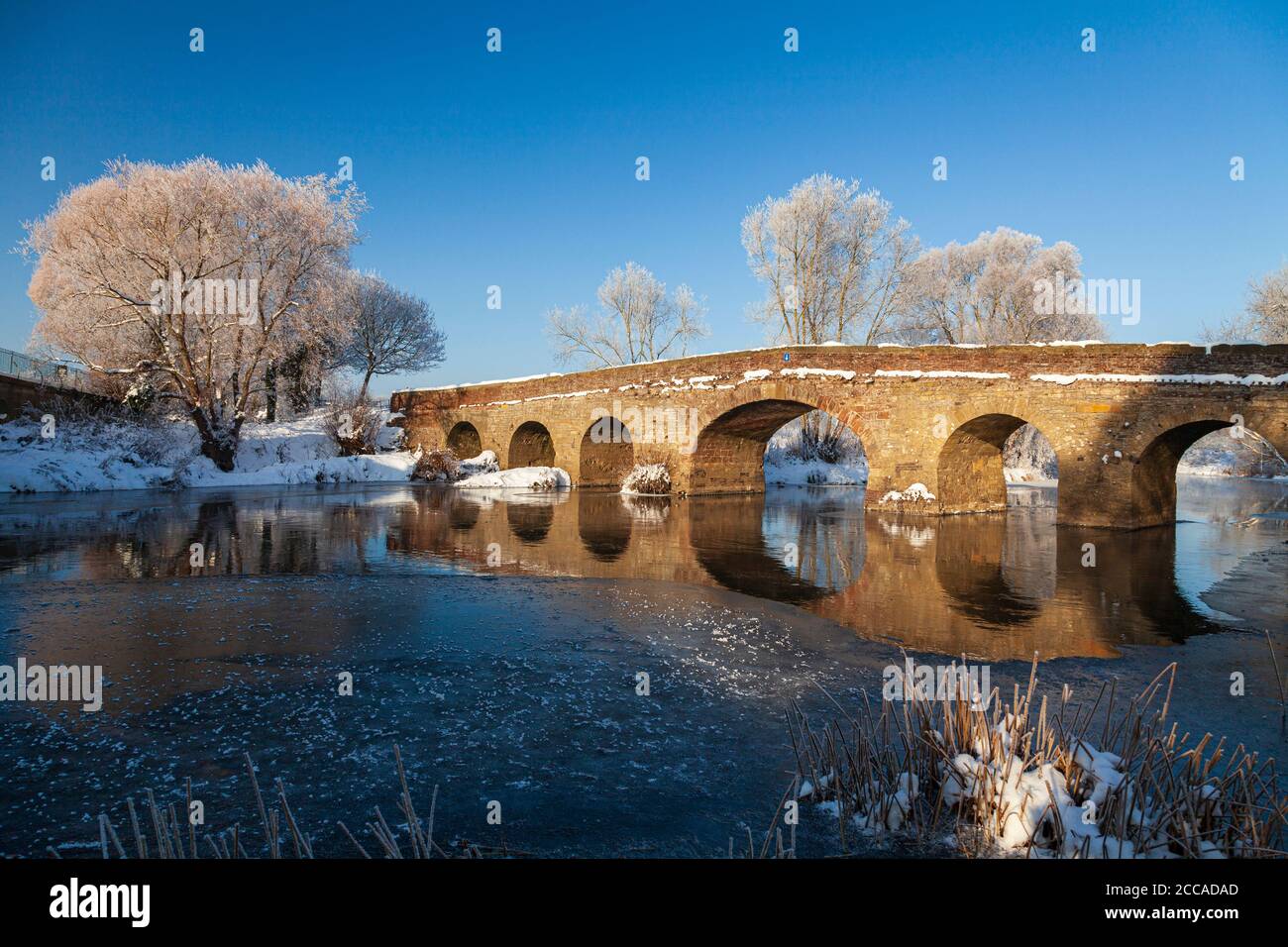 La neve coperto 15 ° secolo Pershore Vecchio ponte sul fiume congelato Avon, Worcestershire, Inghilterra Foto Stock