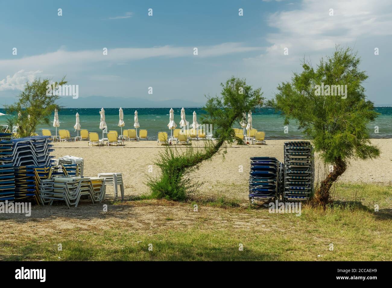 Grecia bar spiaggia vuoto per l'estate dopo covid-19 misure. Vista di giorno di sedie a sdraio e ombrelloni all'aperto senza bagnanti sulla sabbia vicino al mare. Foto Stock