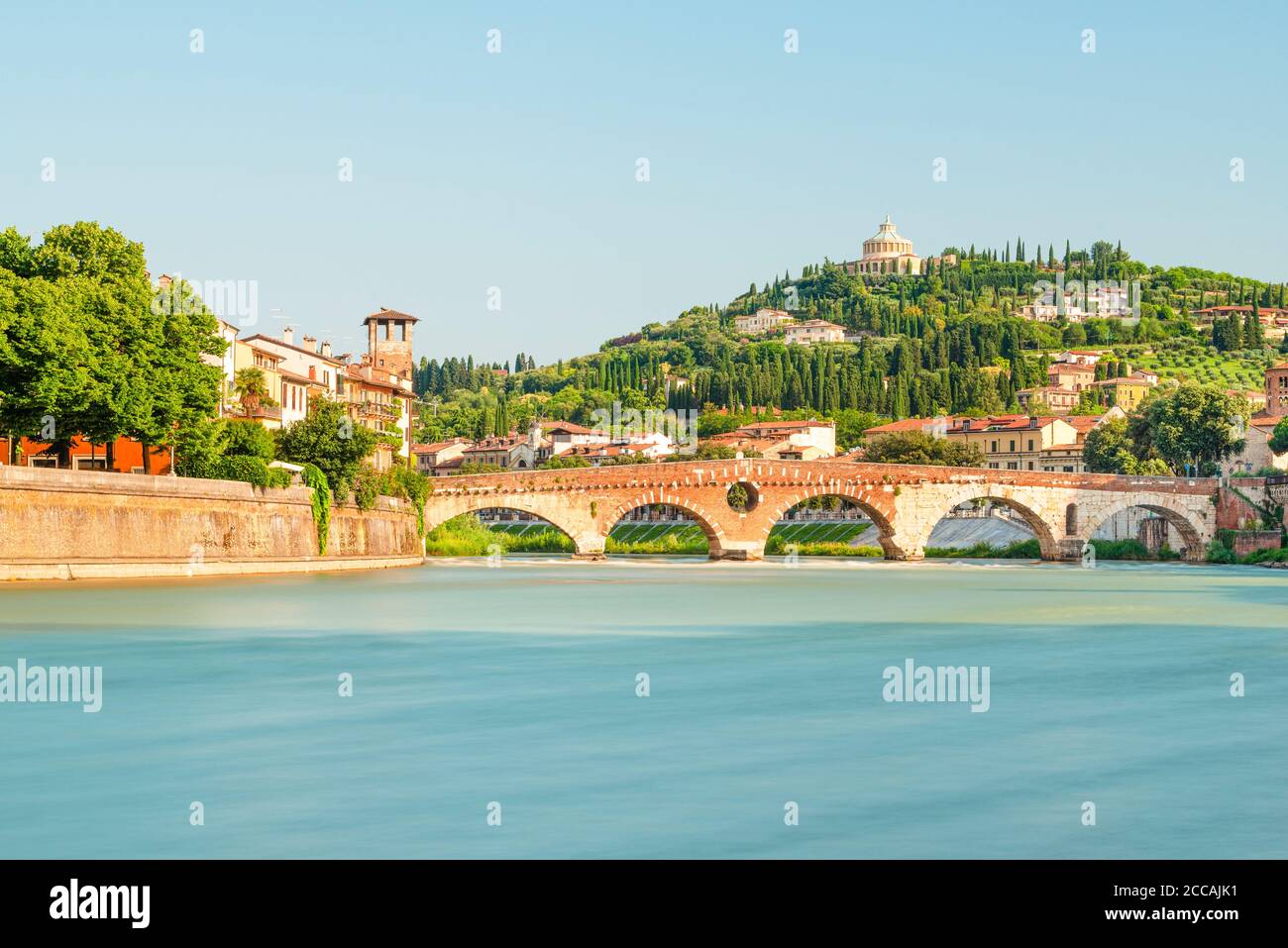 Il ponte romano ad arco di pietra sul fiume Adige nel centro storico di Verona, di fronte al paesaggio mediterraneo al sole del mattino, Italia Foto Stock