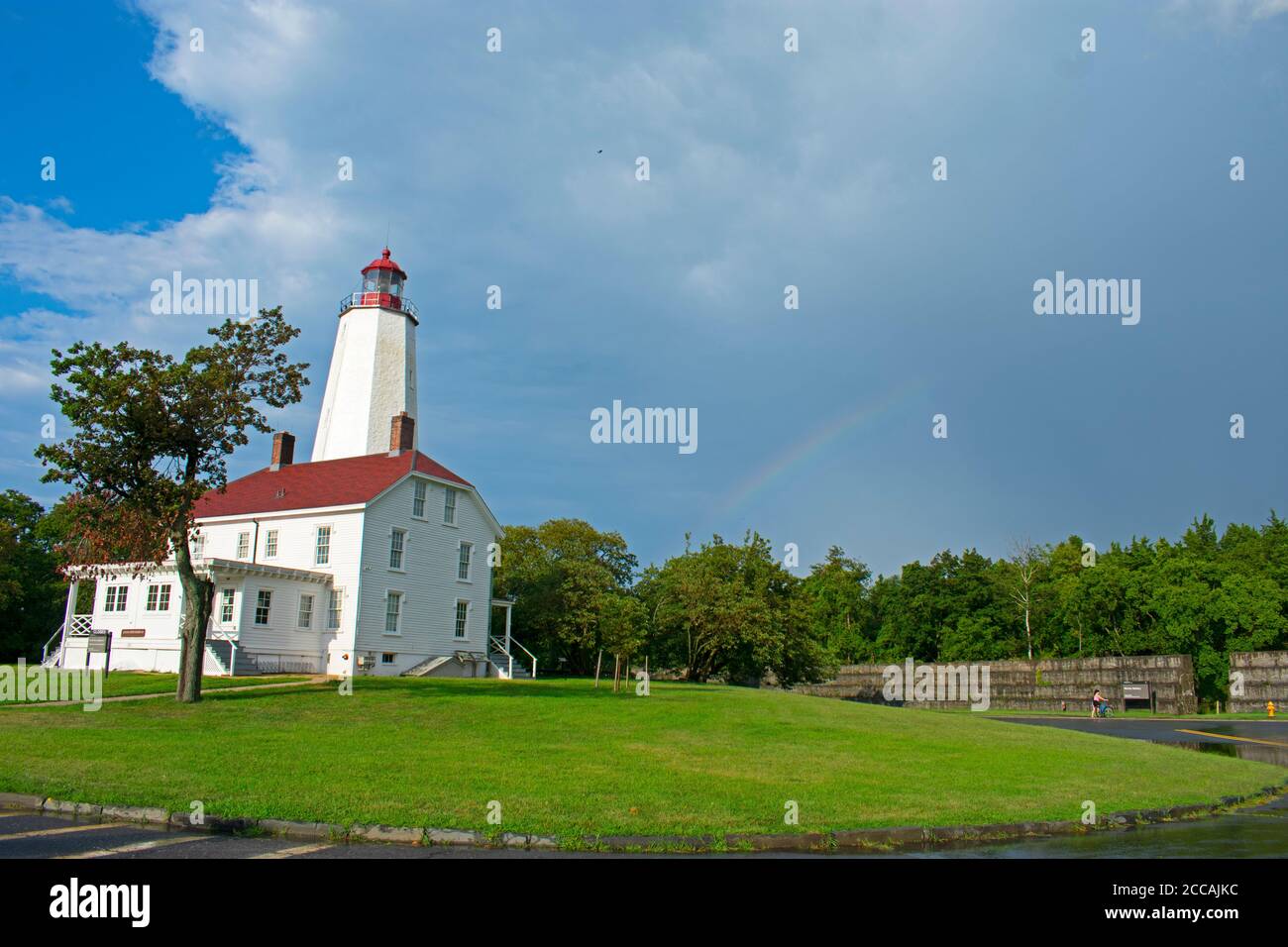 Faro a Sandy Hook, New Jersey e un arcobaleno visibile, dopo una breve ma pesante doccia a pioggia Foto Stock