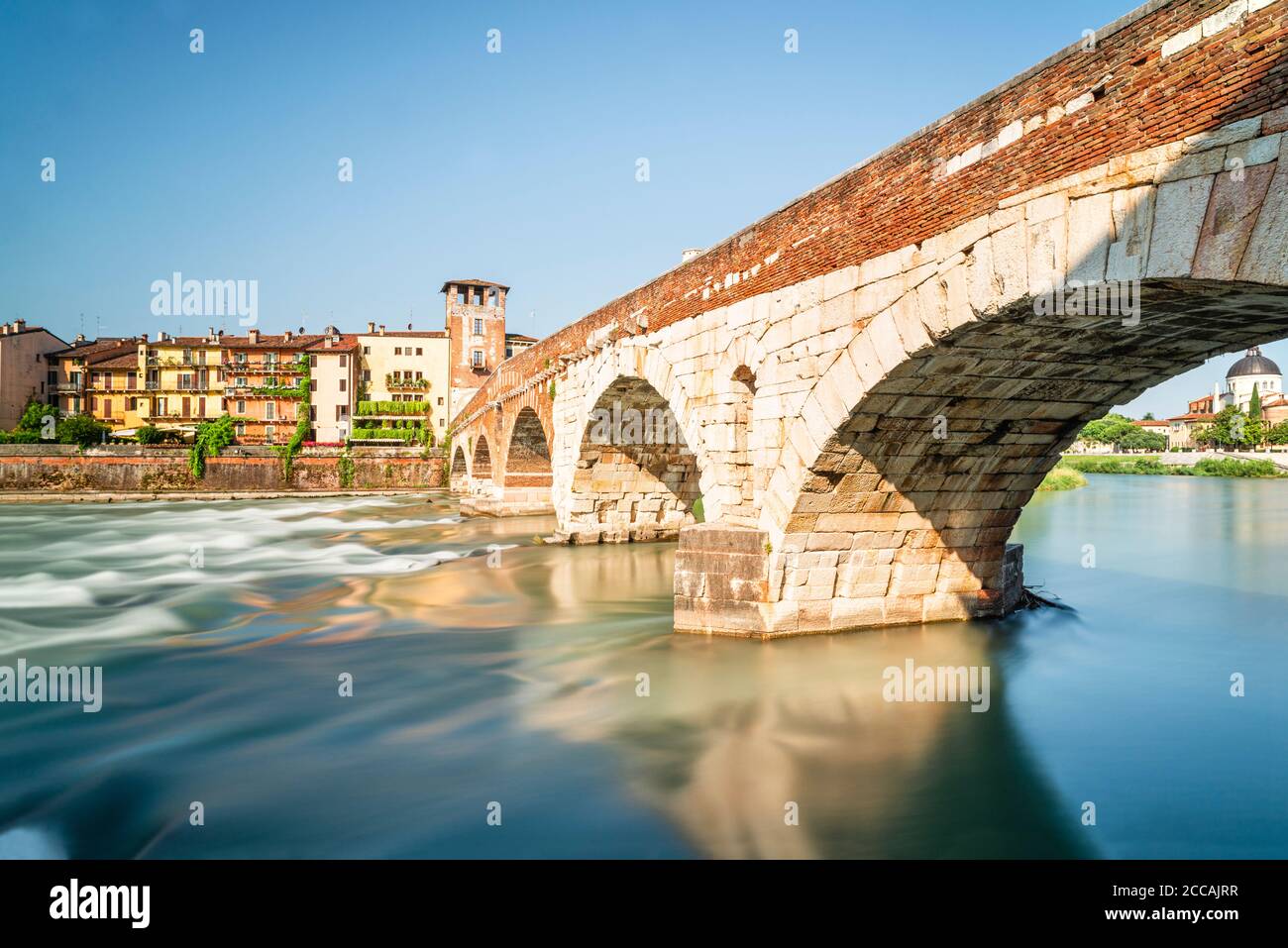 Il ponte romano ad arco di pietra sul fiume Adige con il panorama del centro storico di Verona al sole del mattino, Veneto, Italia Foto Stock