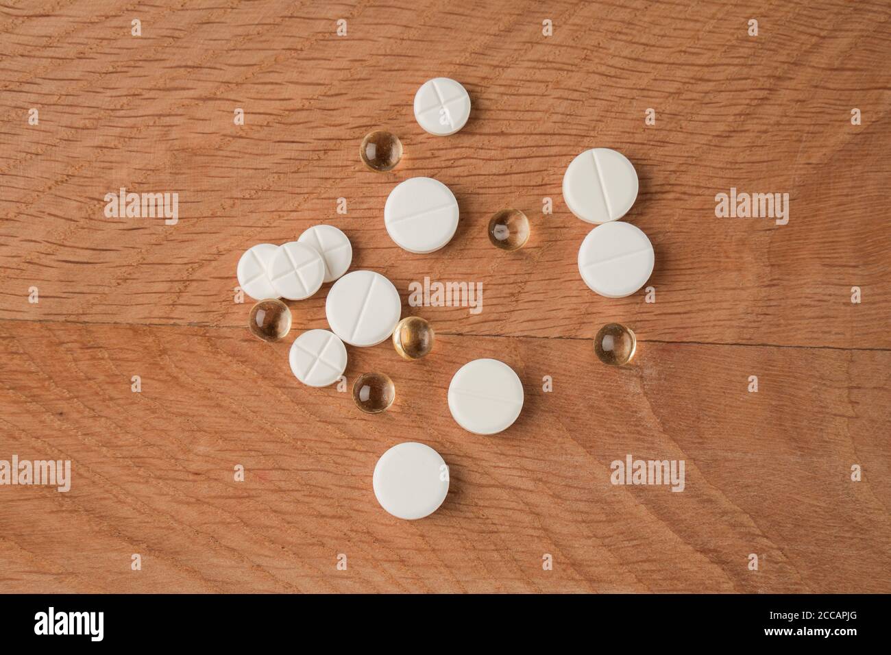 Un mazzo di vari farmaci, pillole che si trovano in giro senza imballaggio, su una tavola di legno Foto Stock