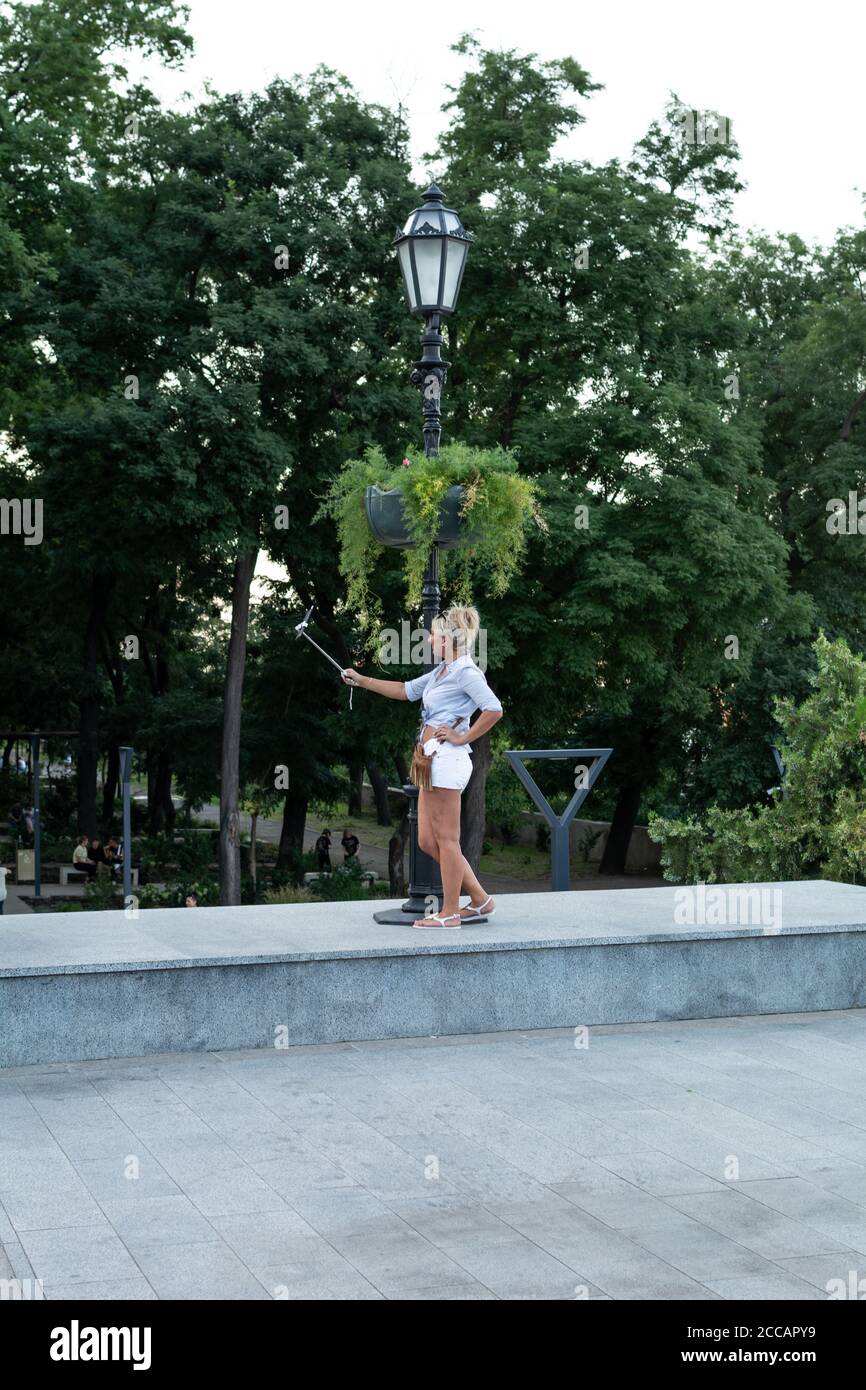 Odessa, Ucraina - 23 agosto 2019 la ragazza fa un selfie sul telefono usando un bastone del selfie. Foto Stock