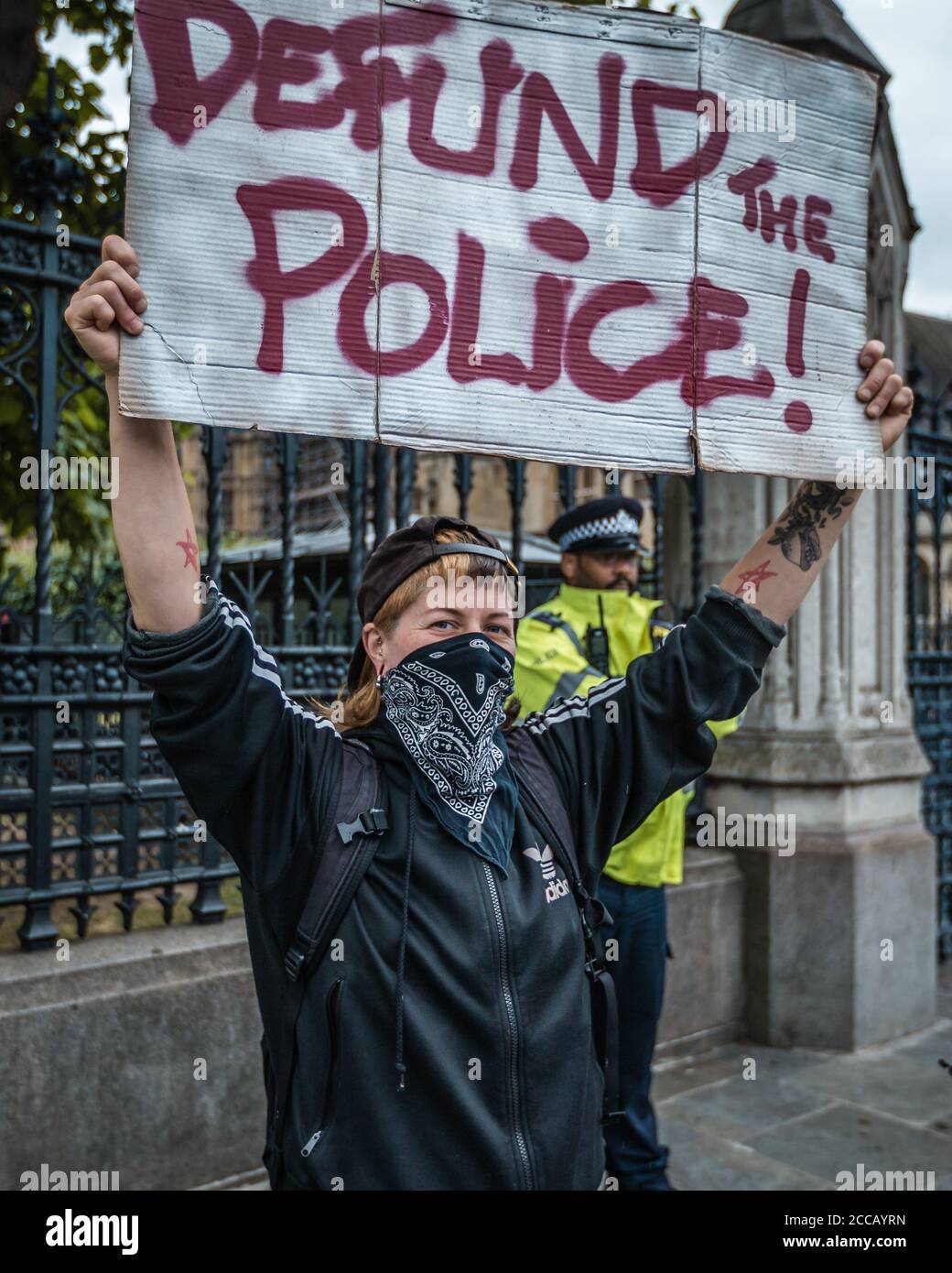 Il manifestante tiene il cartello "defund the police" al di fuori del parlamento dopo L'uccisione di George Floyd e durante il blocco pandemico Foto Stock
