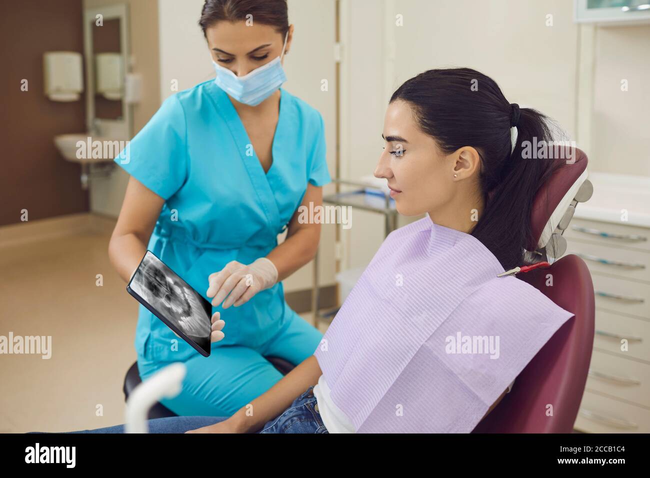 Dentista che mostra la vista panoramica dei denti a raggi X per la paziente Foto Stock