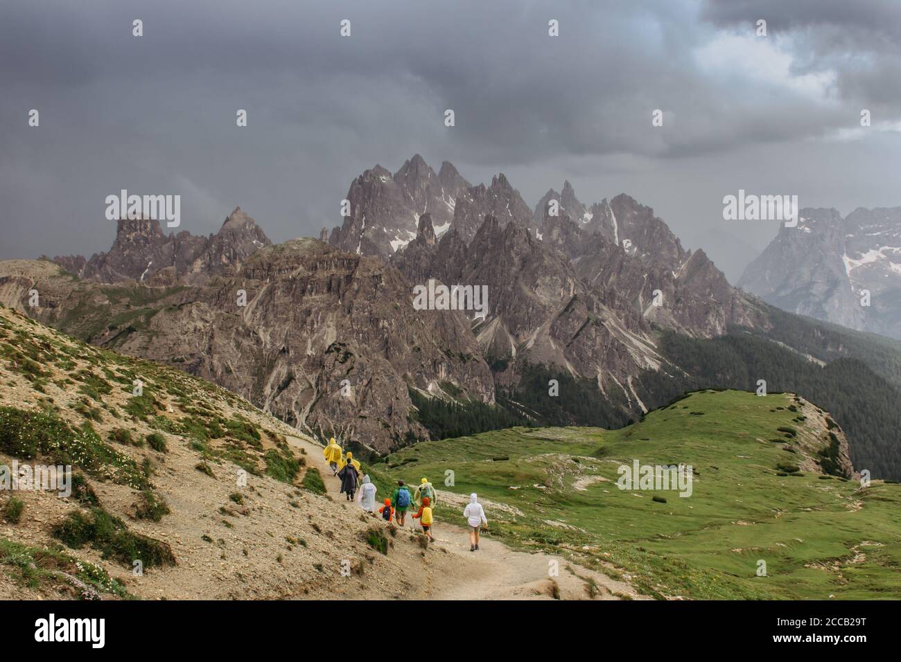 Persone in impermeabile escursioni in Dolomiti,Italy.Rainy giorno all'aperto. Vista del paesaggio montano con nubi buie tempesta. Nubi drammatiche sulle vette o Foto Stock