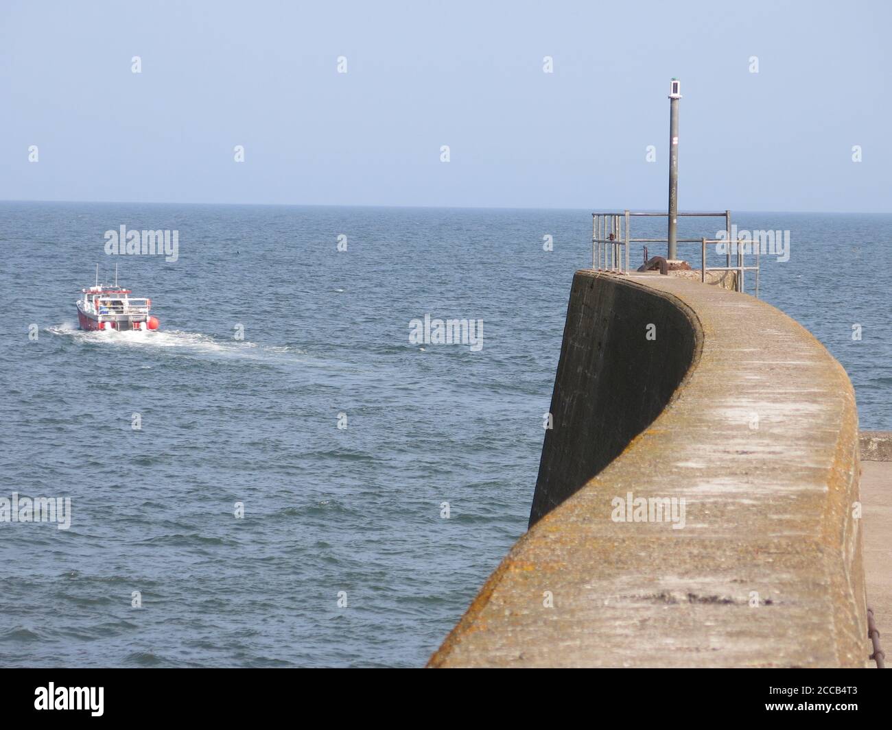 Vista sul mare e su una barca da pesca che lascia il porto; vista dalla fine del molo a St Andrews, Fife, la costa orientale della Scozia. Foto Stock