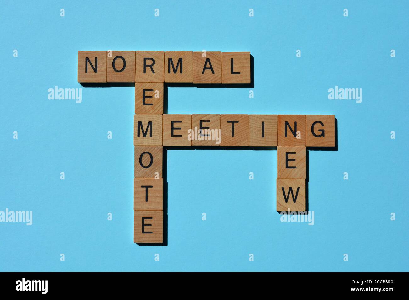 Nuovo normale, remoto, riunione, parole, in lettere alfabetiche in legno in forma di crossword isolato su blu Foto Stock
