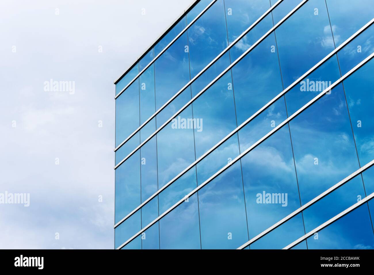 Vista esterna della tipica facciata di vetro blu di un moderno edificio per uffici. Riflessione del cielo. Foto Stock
