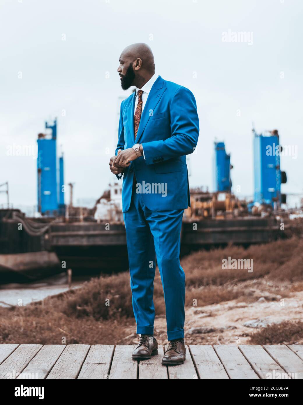 Un ragazzo nero di baldone maturo alla moda che si erge all'aperto in un  elegante costume blu con cravatta, in scarpe di pelle, con tre costruzioni  blu in Foto stock - Alamy