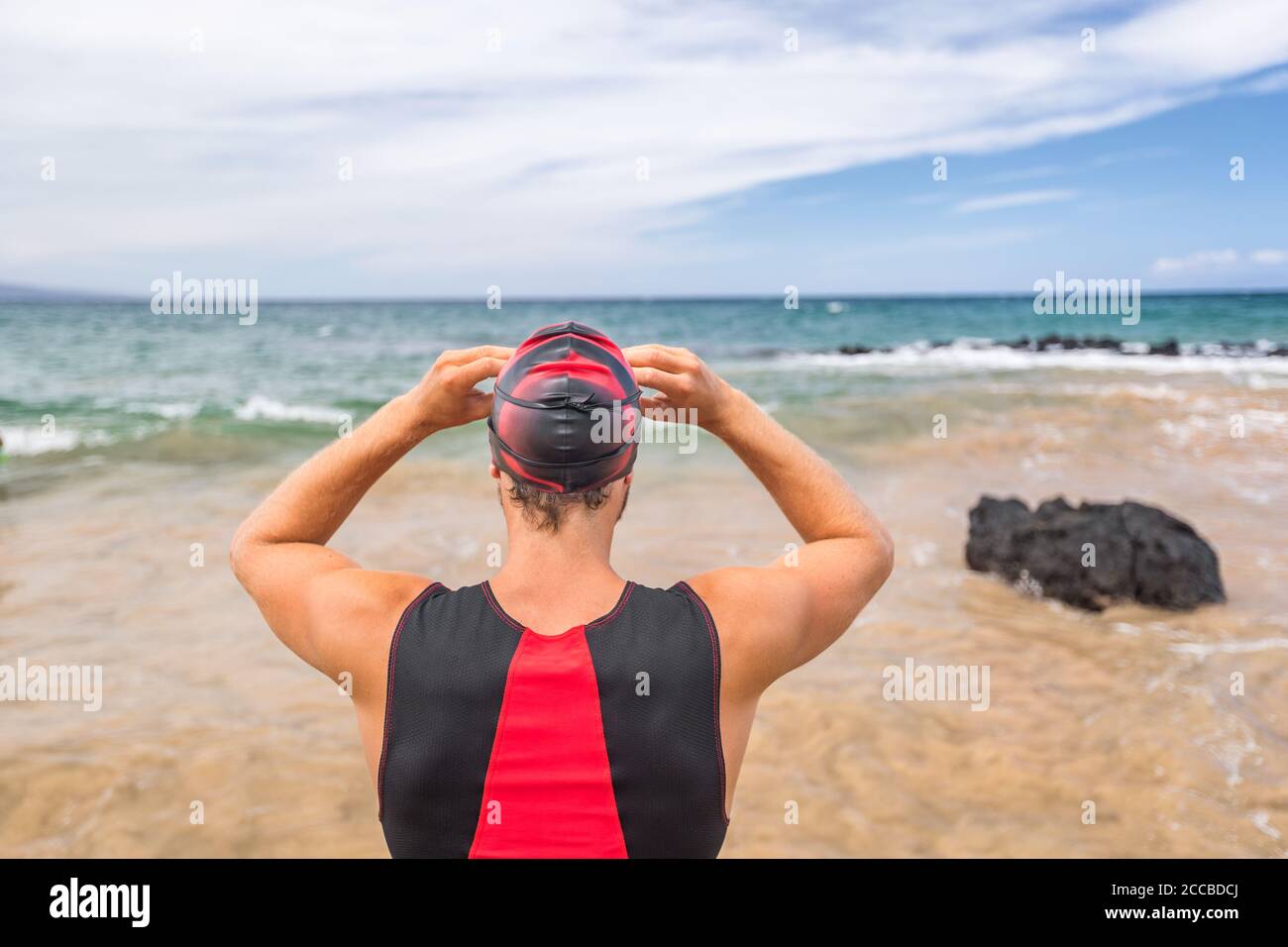 Nuotatore di Triathlon che va nuotando pronto per nuotare guardando l'orizzonte dell'oceano. Uomo triatleta nuotatore indossare occhiali per la concorrenza. Atleta professionista Foto Stock
