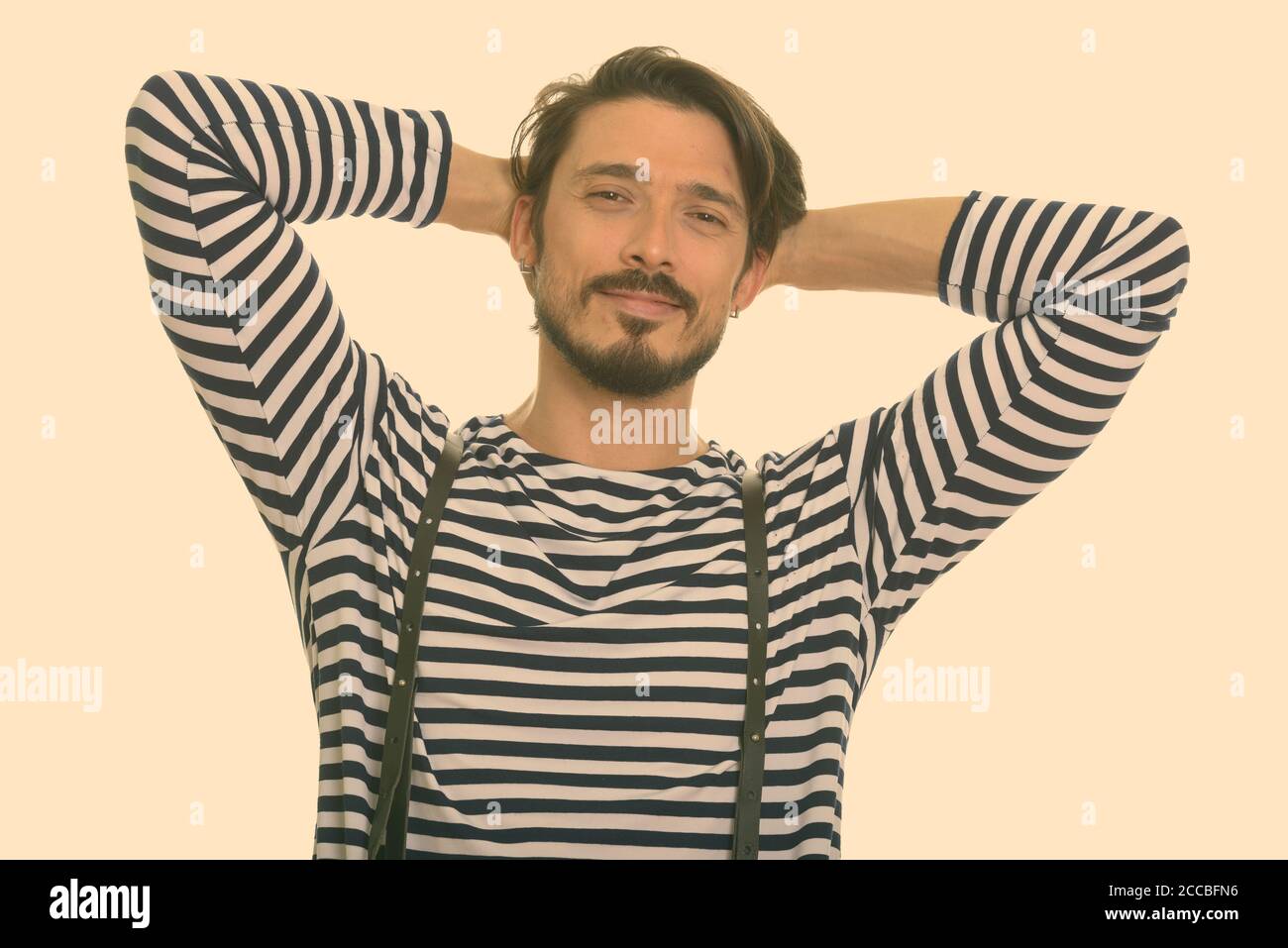 Studio shot di felice bel uomo sorridente con le mani sulla testa Foto Stock