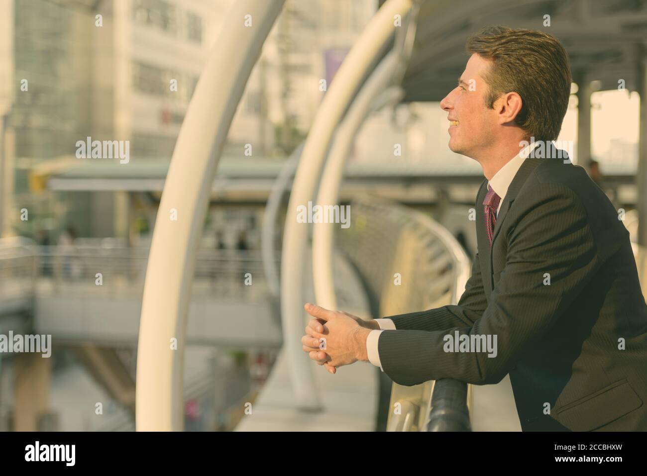 Vista di profilo di happy businessman sorridente e pensare in passerella a Bangkok City Foto Stock