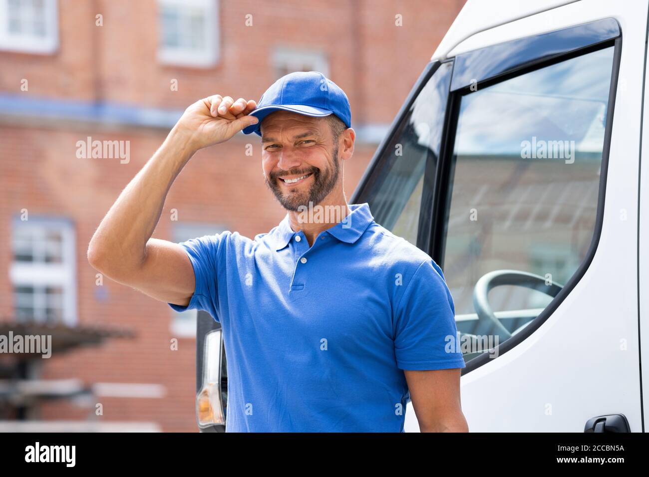 Smiling Delivery uomo o Handycam in uniforme vicino al camion Foto Stock
