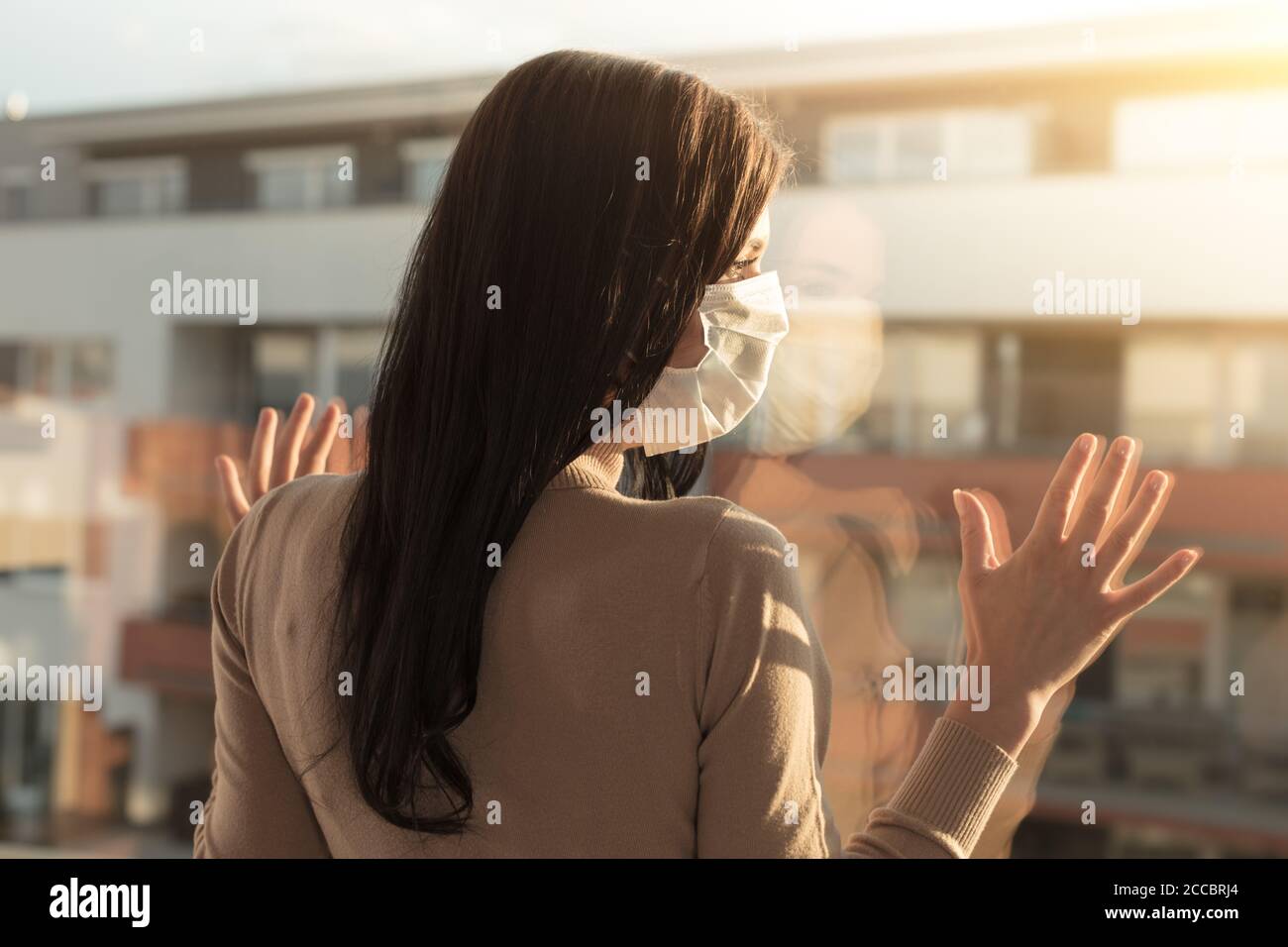 Giovane donna con velo che guarda la finestra, concetto di isolamento domestico. Covid-19 situazione pandemica in auto isolamento a casa. Il nuovo virus corona cambia la norma Foto Stock