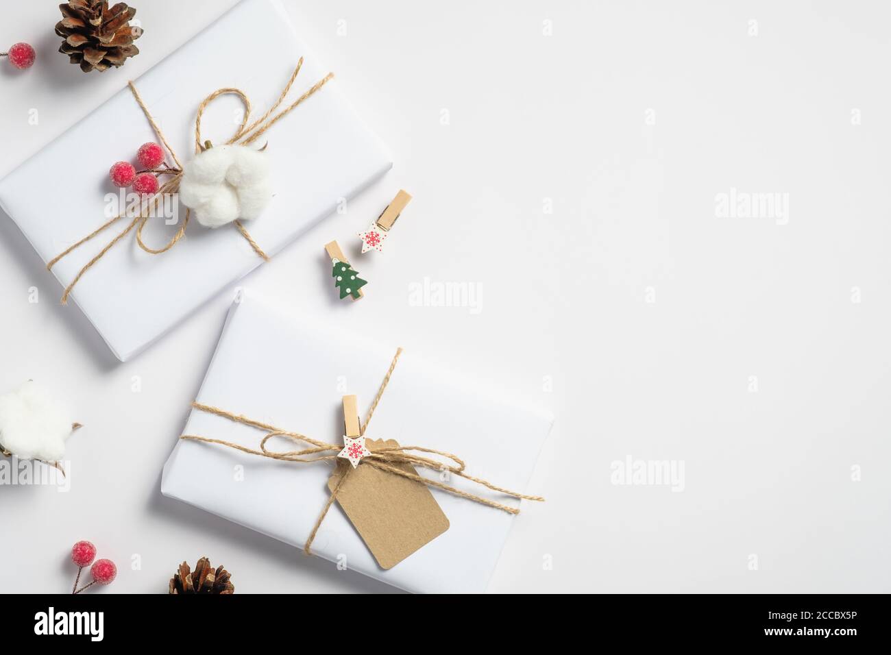 Decorazioni natalizie eco-compatibili e confezioni regalo su sfondo bianco. Disposizione piatta, vista dall'alto. Stile minimalista. Foto Stock