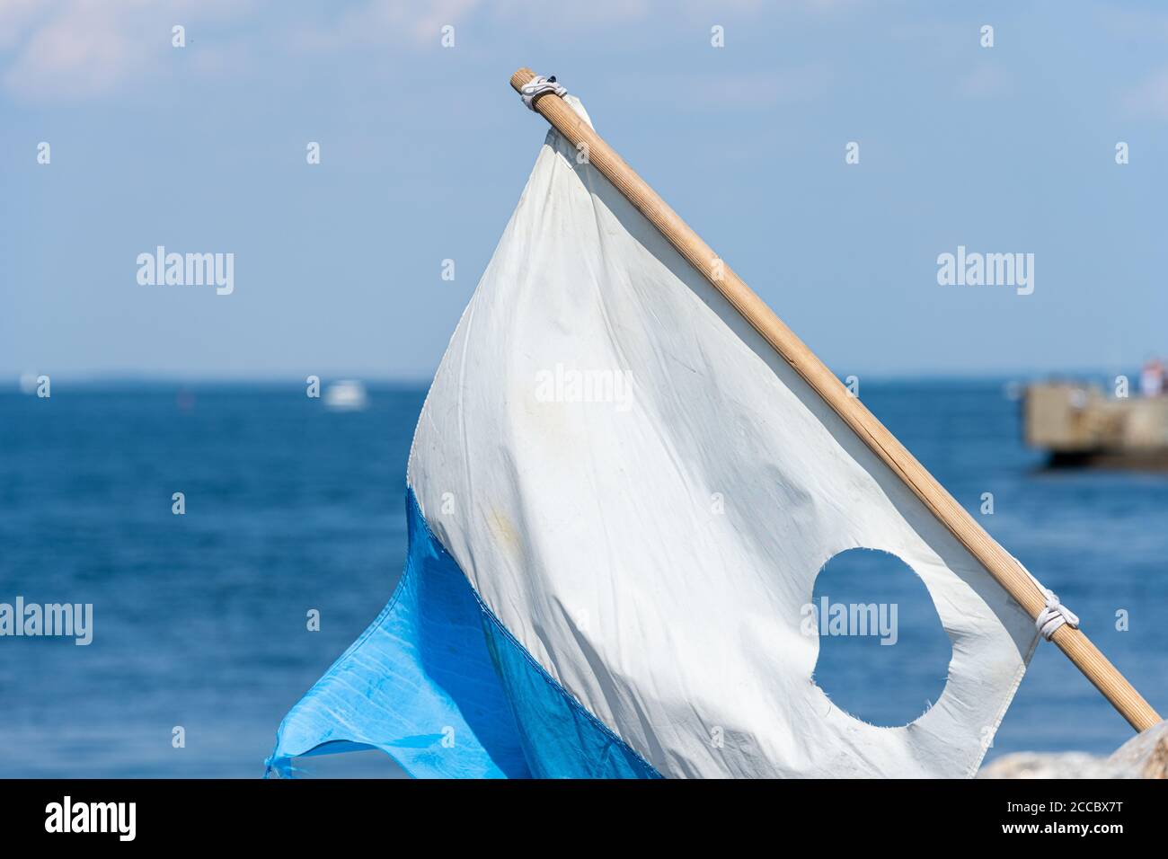 Immagine in primo piano di una bandiera blu e bianca. Oceano blu sullo sfondo Foto Stock