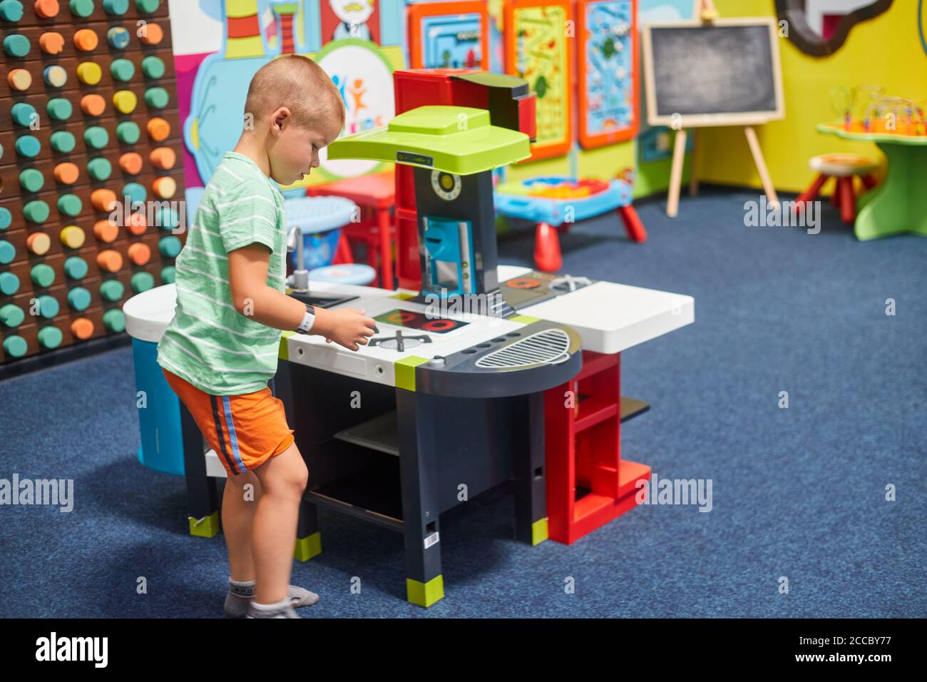 piccolo ragazzo che gioca nella cucina dei bambini Foto Stock