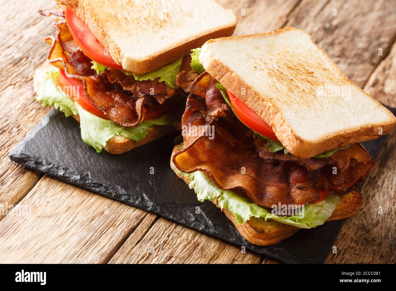 Delizioso panino blt con pancetta, insalata di iceberg e pomodori primo piano su una tavola di ardesia sul tavolo. Orizzontale Foto Stock