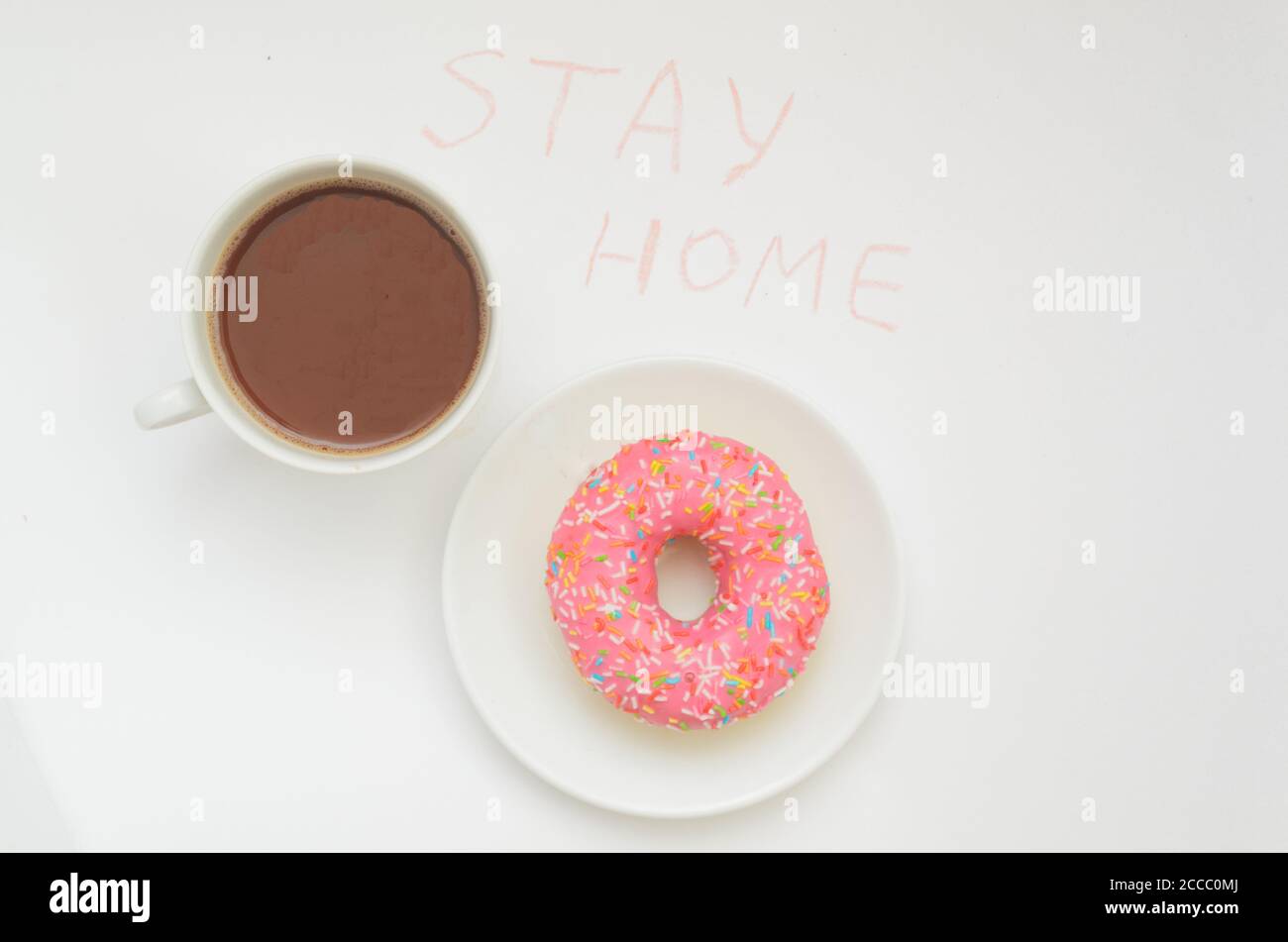 Vista dall'alto, una tazza di cacao e un bicchiere rosa Donut su sfondo bianco.Sweet dessert.Stay casa in caldo Foto Stock