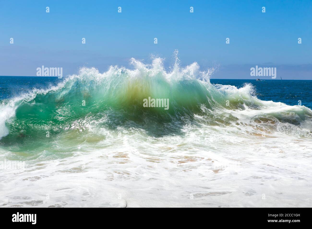 Spruzzi d'acqua bianca e sabbia che vengono tirati verso l'alto dal fondo da un'onda di rottura presso i famosi cilindri del punto di surf. Newport Beach, California; Stati Uniti Foto Stock