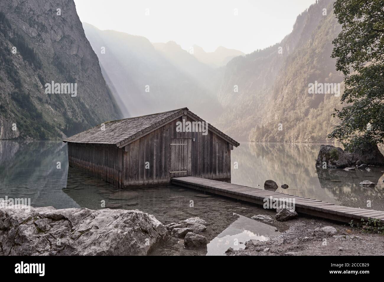Boathouse al lago Obersee in una mattina misteriosa a Schoenau am Koenigssee, Germania Foto Stock